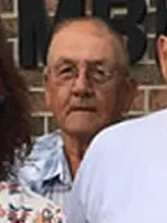 Portrait of John, a man wearing a blue shirt and looking at the camera.