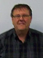 A smiling man named Brian wearing glasses and a plaid shirt.