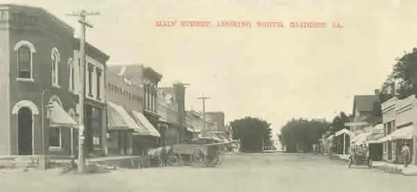 An antique postcard depicts a street lined with buildings and horses.