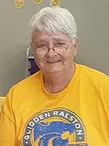 An older woman, Pat Rose, wearing a yellow shirt. She is a member of the Glidden Library Board of Trustees.