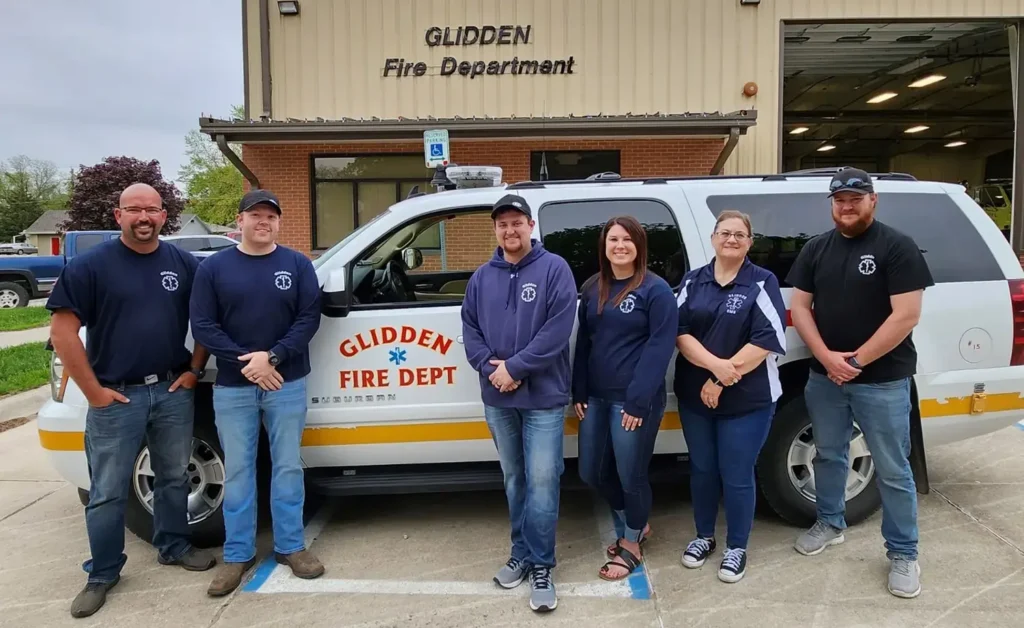 Glidden EMS in front of fire department building and vehicle.