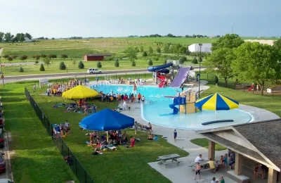A spacious outdoor pool with a water slide and playground equipment.